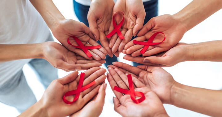 Group of young women with red ribbons in hands are struggling against HIV/AIDS. AIDS awareness concept.