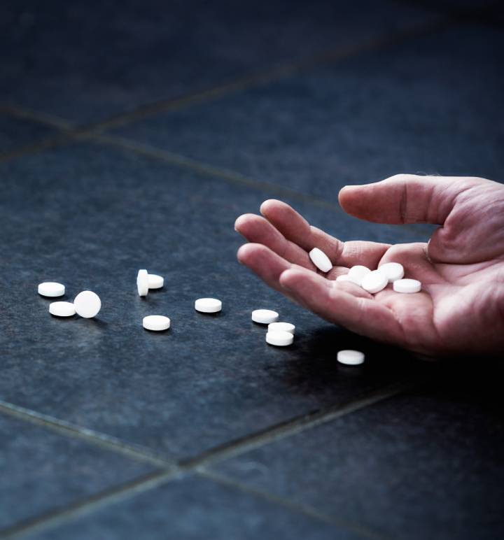 open hand with pills scattered on table