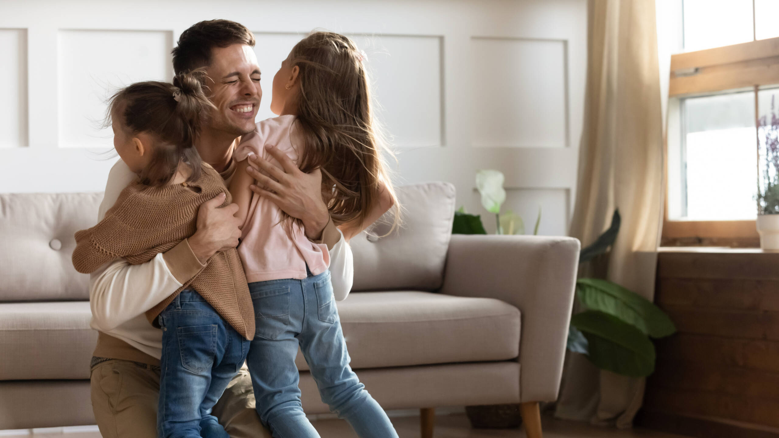Father hugging two daughters