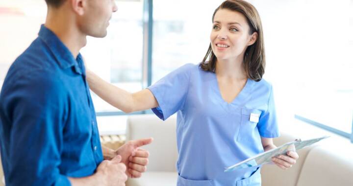 Nurse comfortingly puts hand on male patient's shoulder